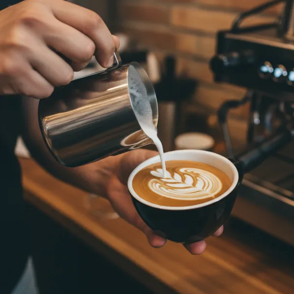 A skilled barista pouring intricate latte art into a cup, showcasing the smooth, velvety, and integrated microfoam that makes such designs possible.