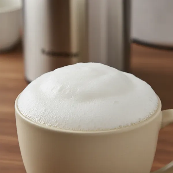 Close-up of perfectly frothed, silky milk in a mug, ready for pouring or latte art.